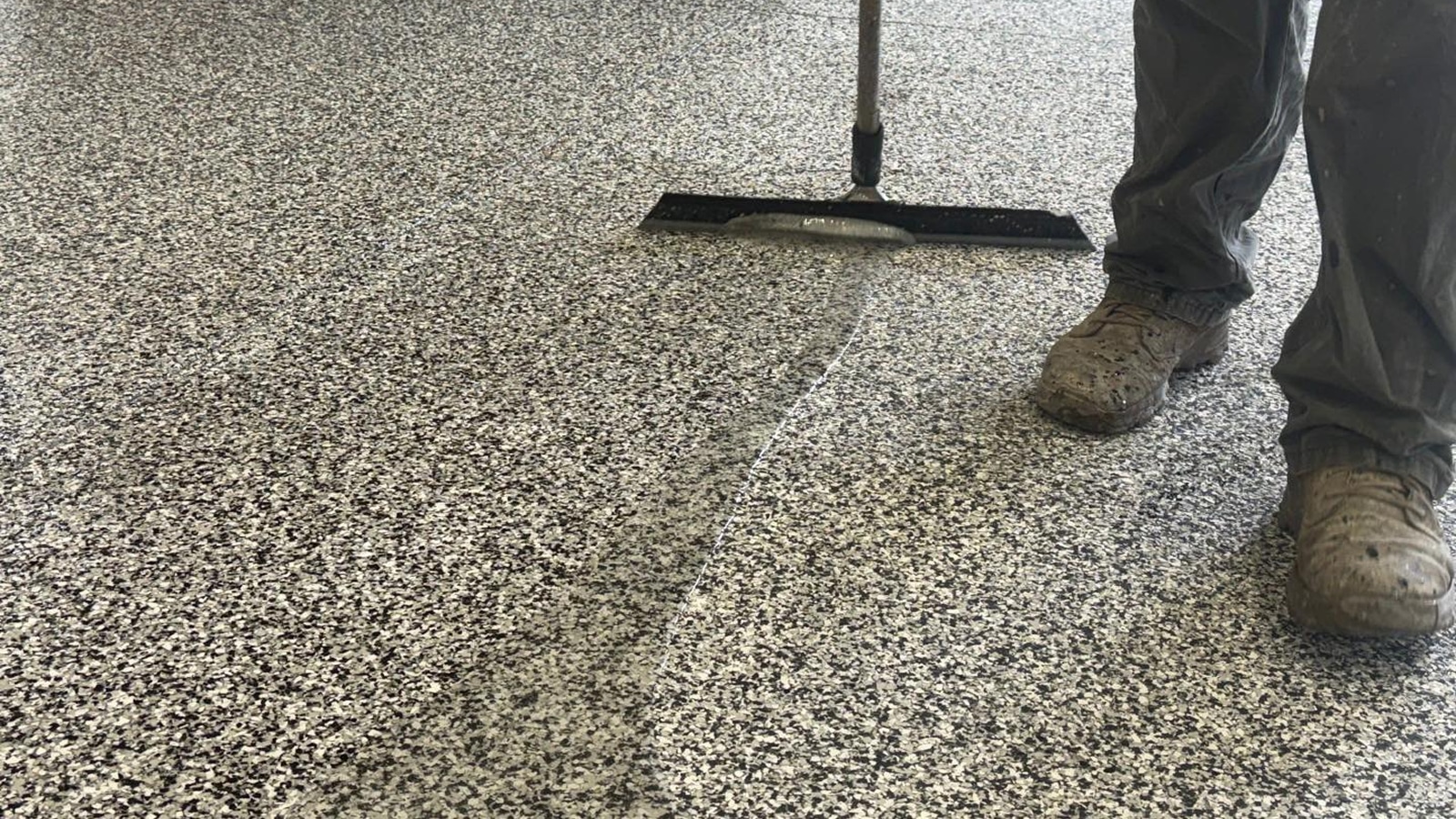 Technician applying a one-day garage floor coating, featured in Sullivan's Concrete Coatings' installation guide